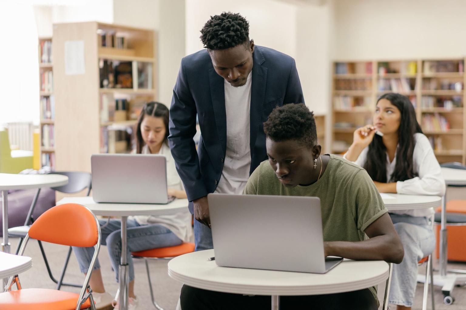 Mentor guiding student at laptop